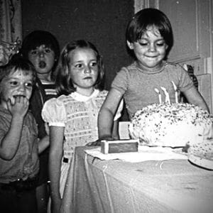 Marco Enríquez-Ominami en su cumpleaños escolar, sonriendo frente a una torta con velas, rodeado de compañeros.